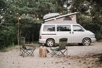 Class B RV Camper Van at a sandy campsite with chairs and a string of lights