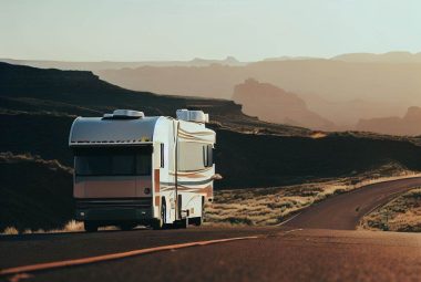 RV on side of open road with forested mountains in background